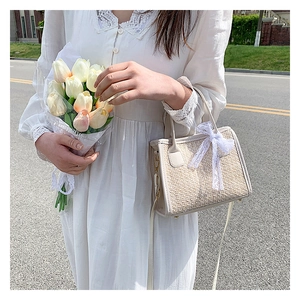 Sac bandoulière tissé beige avec bordure en dentelle blanche et pendentif nœud élégant