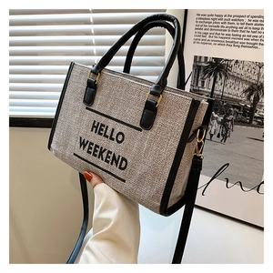 Close-up of canvas tote bag with HELLO WEEKEND text and premium black leather handles