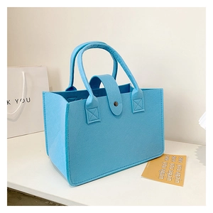 Detailed close-up of bright blue felt tote bag featuring reinforced stitching and top fastener
