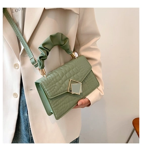 Crossbody bag in green crocodile pattern with unique gathered handle and metal buckle