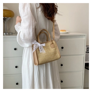 Sac à bandoulière en paille avec nœud en dentelle et garniture en cuir sur robe blanche