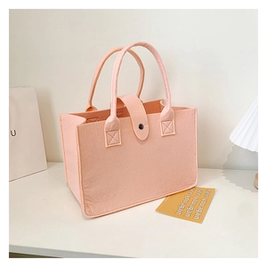 Detail of pink felt tote bag featuring reinforced stitching and leather snap closure