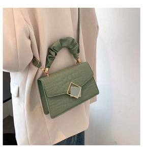 Detail of avocado green crocodile pattern handbag with ruched handle and gold clasp