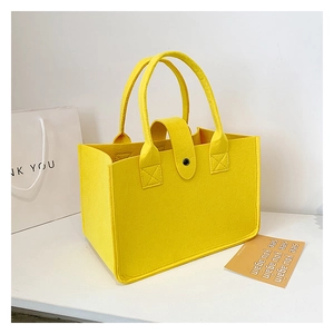 Detail of yellow felt tote bag featuring a black snap button closure and sturdy handles