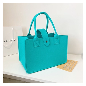 Detail of cyan blue felt tote bag with metal buckle closure and textured finish