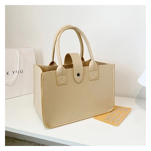Detail of felt tote bag with snap button closure and cylindrical handles in beige