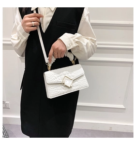 Détail du sac à main blanc motif crocodile avec boucle dorée et poignée plissée