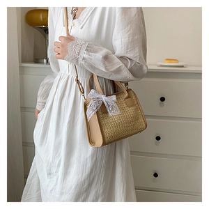 Sac bandoulière en paille avec nœud en dentelle et bandoulière porté par mannequin
