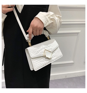 Detail of white crocodile pattern bag with gold chain and cloud handle on a model
