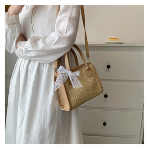Détail du sac en paille tressée avec ruban en dentelle blanche et lanières en cuir crème