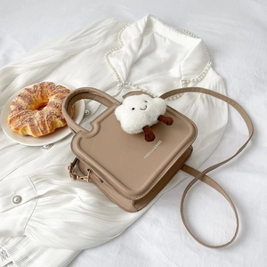 Brown toast-shaped crossbody bag with white plush cloud charm on casual white background