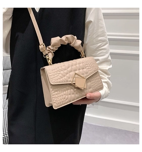 Detail of light beige crocodile embossed crossbody bag with gold metal geometric clasp