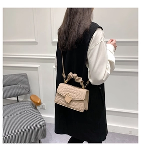 Detail of beige crocodile pattern bag with ruched handle and large gold metal buckle