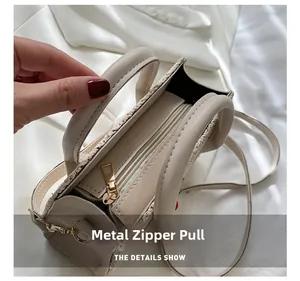 Top detail of cream woven crossbody bag featuring metal zipper pull and leather handles