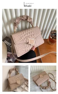 Détail du sac bandoulière kaki avec motif crocodile, poignée froncée et fermoir métal
