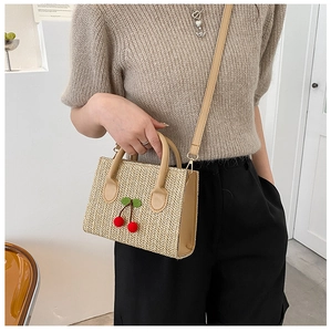 Detailed shot of woven crossbody bag featuring 3D cherry accents and leather straps