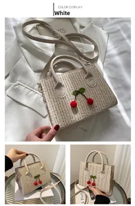 Close-up of woven herringbone texture and cherry pompom detail on white straw crossbody bag