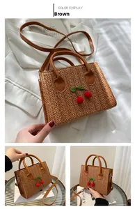 Detailed close-up of woven bag featuring 3D cherry embroidery and adjustable strap
