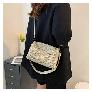 Detail of cream woven pillow bag with gold chain and wide shoulder strap on model
