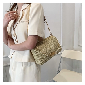 Detailed close-up of woven shoulder bag with gold clover buckles and leather strap