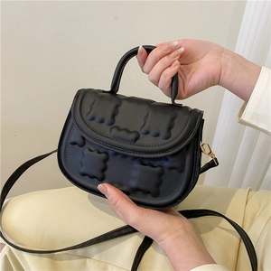 Women's black quilted biscuit saddle bag with top handle and golden hardware crossbody