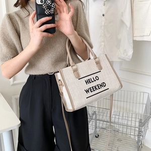 Chic canvas tote bag with HELLO WEEKEND text and leather handles on a casual shoulder strap