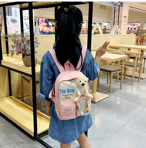 Zaino per bambini rosa e bianco indossato da un modello con decorazione a orsetto