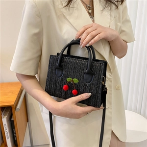 Fashionable black woven crossbody bag with red cherry detail and leather shoulder strap