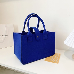 Minimalist royal blue felt tote bag with metal snap closure in a modern home setting