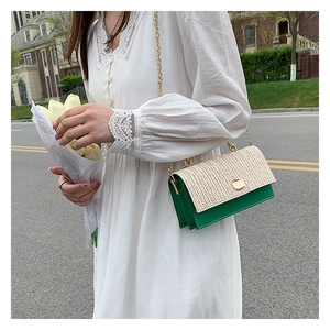 Detail of woven straw flap and dark green leather texture on a stylish chain crossbody bag
