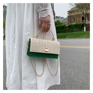Detail of woven straw flap and dark green leather bag with a gold metal ring handle