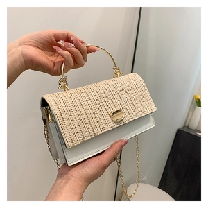 Detail of woven straw flap and gold circular clasp on a white leather shoulder bag