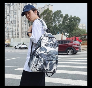 Detail view of graffiti print backpack with 'UNRULY' letters in urban street setting