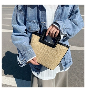 Detailed texture of woven straw tote bag with black leather handle and minimalist contrast