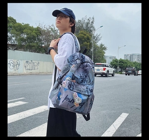 Street style view of a graffiti print backpack and matching navy baseball cap on a crosswalk