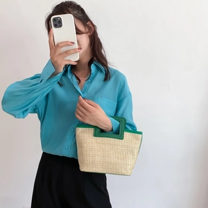 Fashionable woven tote bag with green handles paired with a light blue shirt