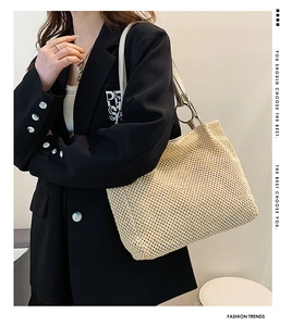 Detail of straw woven tote bag with smooth faux leather straps and metal ring connector