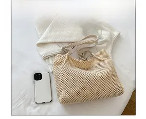 Top view of beige straw tote bag with leather straps and size comparison with a phone