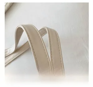 Detail of cream leather handle with reinforced double stitching on woven tote bag