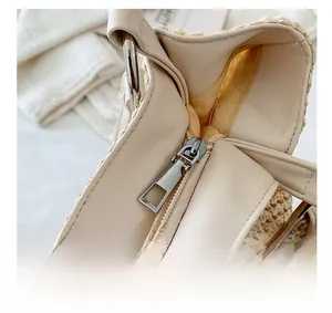 Detail of the smooth metal zipper closure and faux leather trim on the straw tote bag