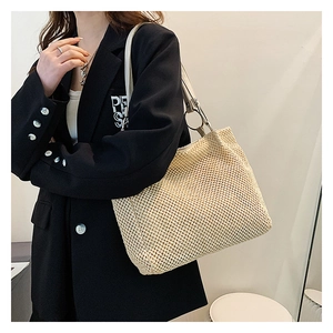 Detail of hand-woven straw tote bag with premium grey leather shoulder straps