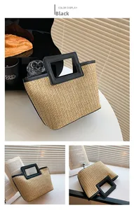 Detail view of woven straw tote bag featuring black geometric cutout handles and natural texture