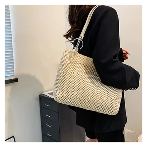 Detail of woven straw tote bag with silver metal rings and wide shoulder strap
