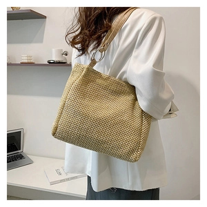 Detail of straw woven tote bag with brown leather strap and silver metal ring connector