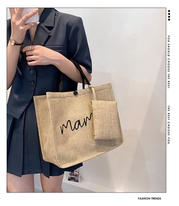 Detail of beige linen tote bag with mama print, featuring black rope handles and a small pouch
