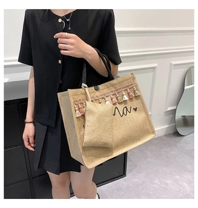 Detail of beige linen tote bag featuring colorful tassels and woven rope handles