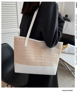 Detail of large straw tote bag with white leather trim shown in a modern office setting