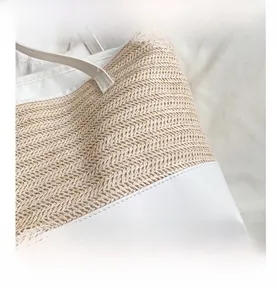 Detail of woven straw pattern with white leather trim and precise stitching for beach bag