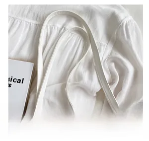 Detail of white leather shoulder strap stitching on a natural straw weave beach tote