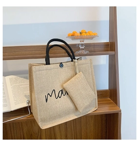 Jute tote bag with black handles and small coin purse on a wooden shelf in a cozy setting